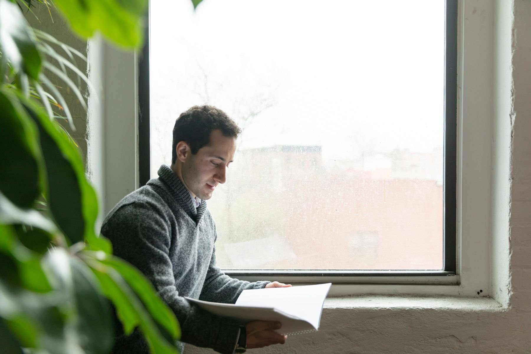A property professional reviewing a document by the window in natural light